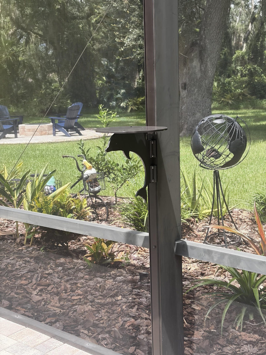 Black dolphin mini table bracket on dark post in garden.