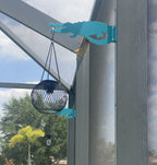 Hanging lanterns on metal alligator bracket outdoors.