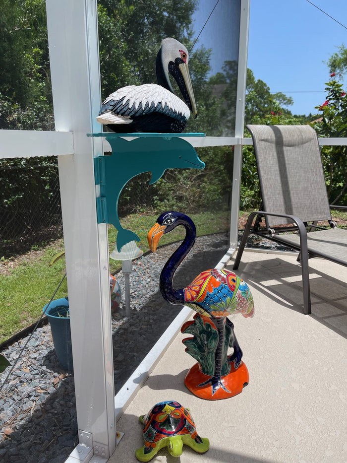 Pelican and flamingo decor with dolphin hanger on white post.