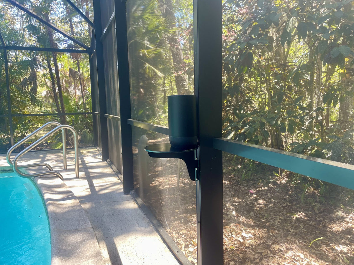 Outdoor speaker beside screened pool area with foliage