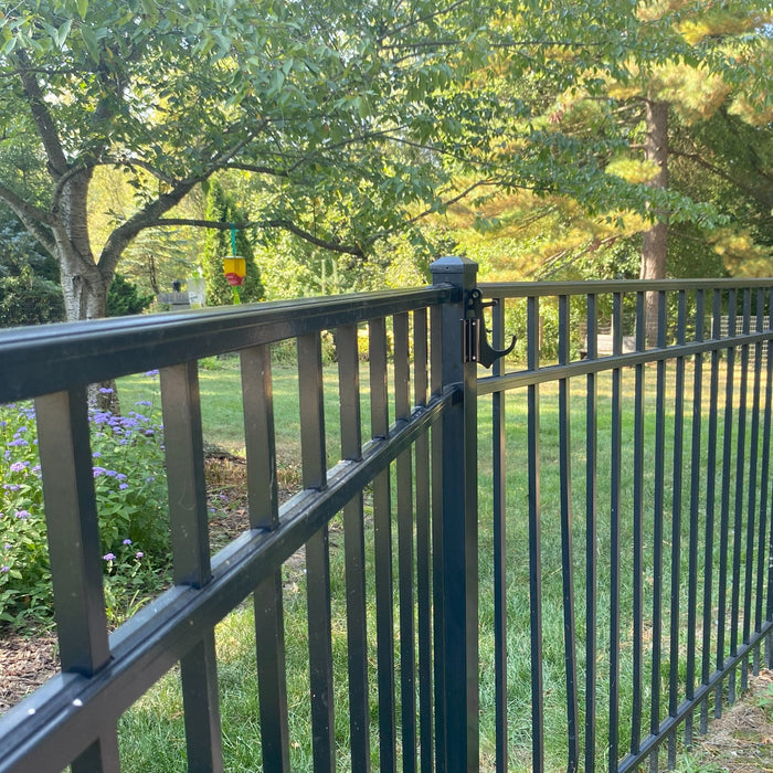 Black aluminum fence with garden, small hook clamped on a post.