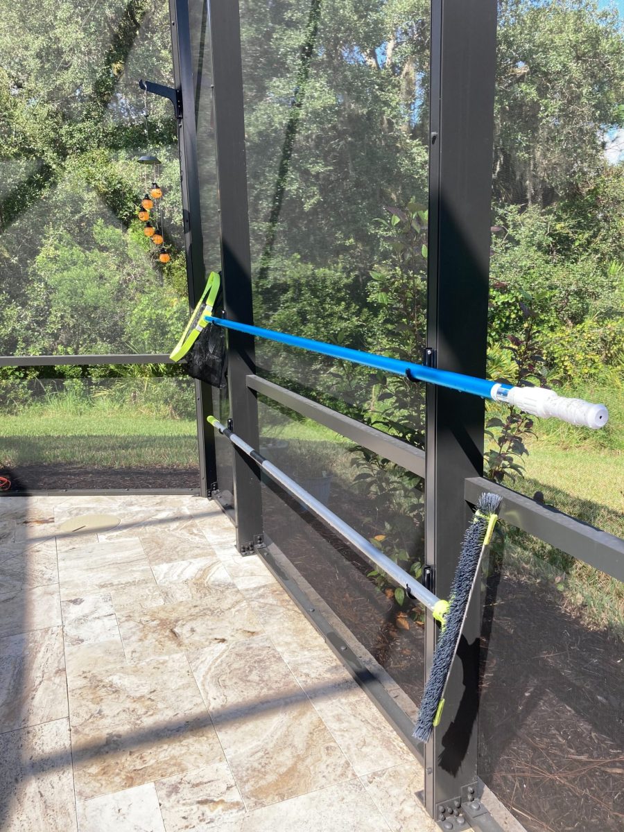 Green hook holding pool pole on dark enclosure.