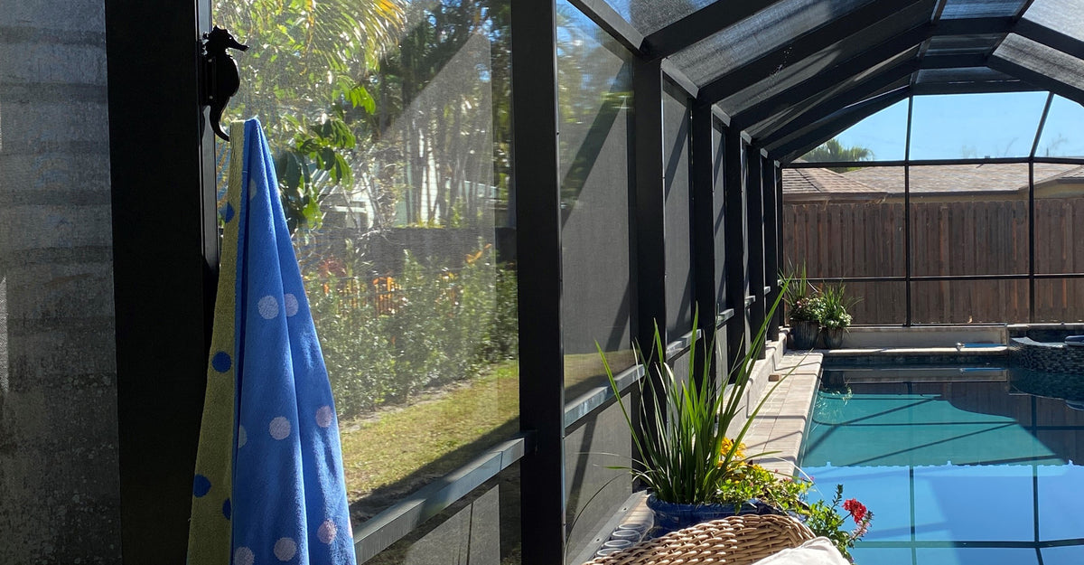 Dark seahorse hook on post holds blue polka-dot towel, pool visible.