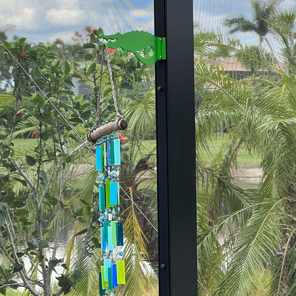 Colorful wind chime hanging by a window, tropical backdrop.