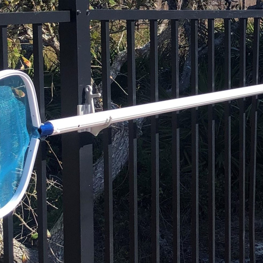 Pool skimmer net on Anchor clamp hook on black aluminum fence.