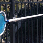 Pool skimmer net by metal fence outdoors.