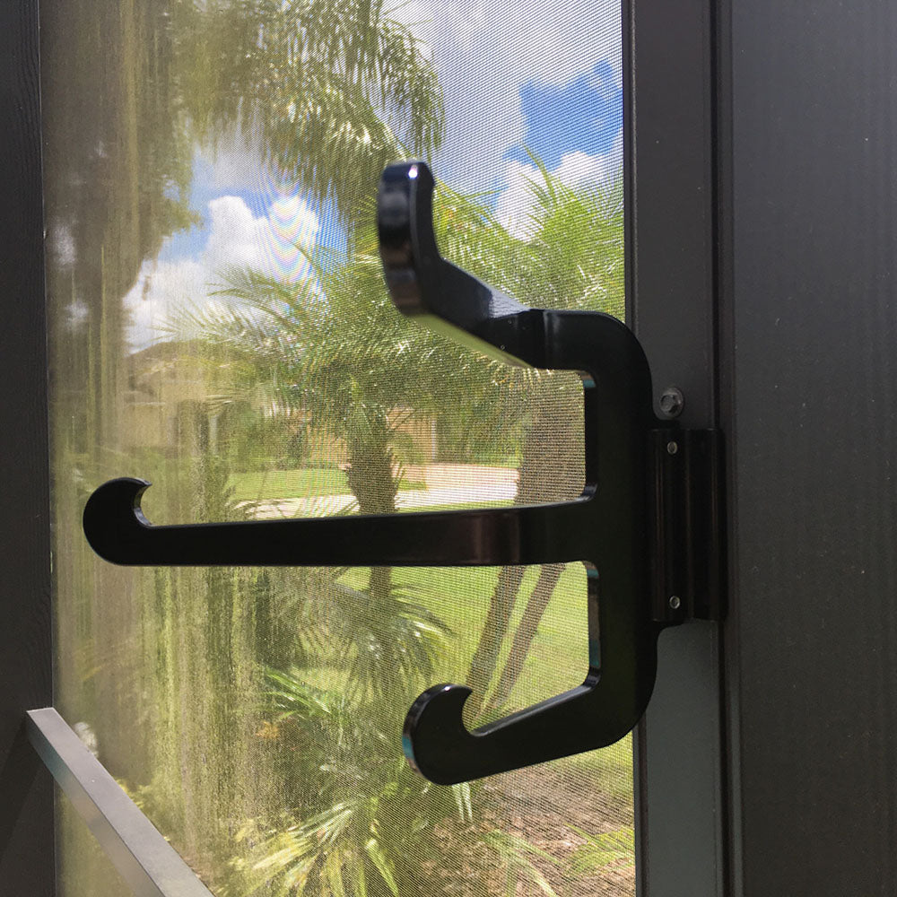 Screen door handle with tropical garden view.