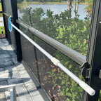 Manual pool cover roller on patio by lake.