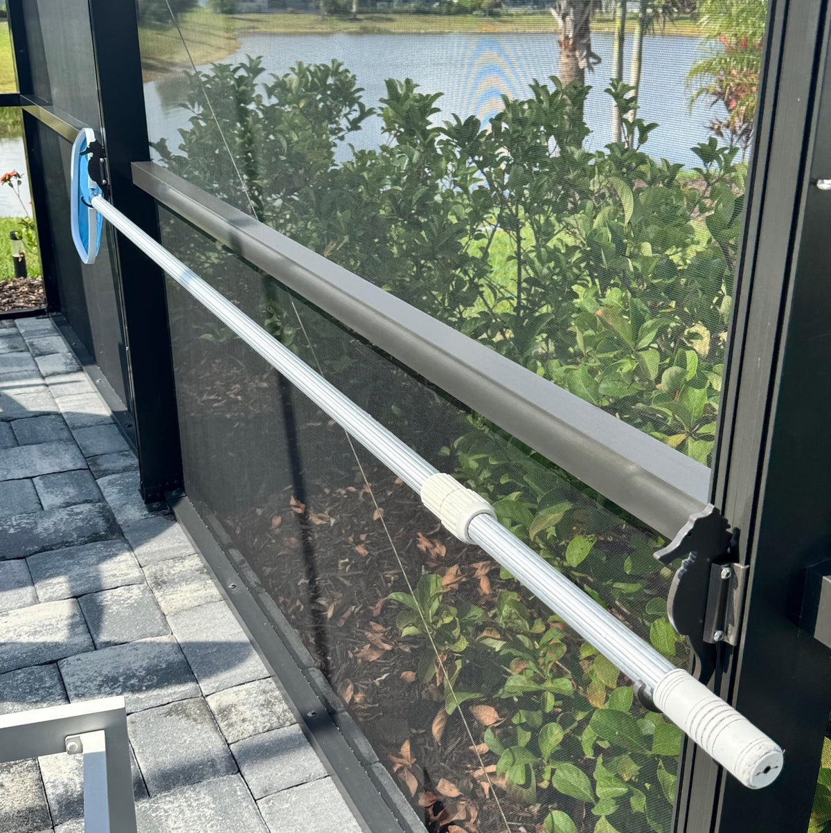 Manual pool cover roller on patio by lake.