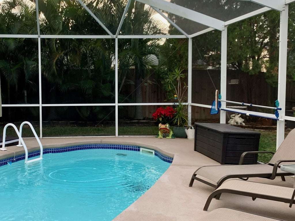 Enclosed backyard pool and patio with loungers.