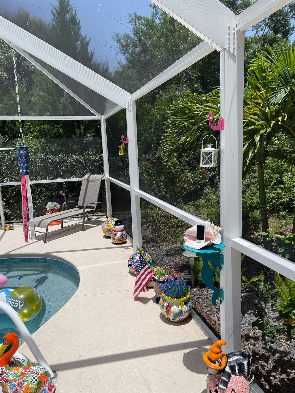 Sunny poolside patio with colorful decorations and screened enclosure.