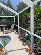 Sunny poolside patio with colorful decorations and screened enclosure.