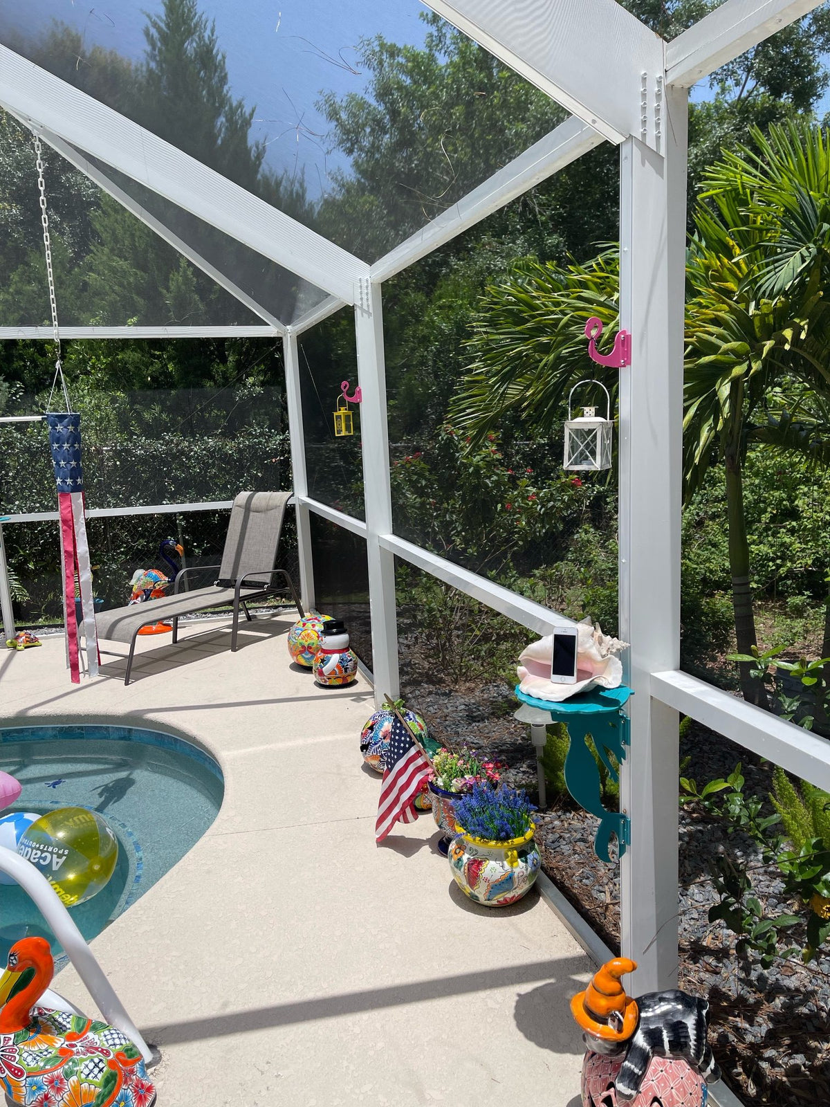 Sunny poolside patio with colorful decorations and screened enclosure.