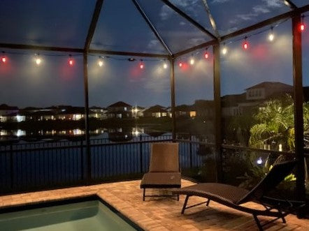 Lanai at dusk with string lights over the pool, lake beyond.