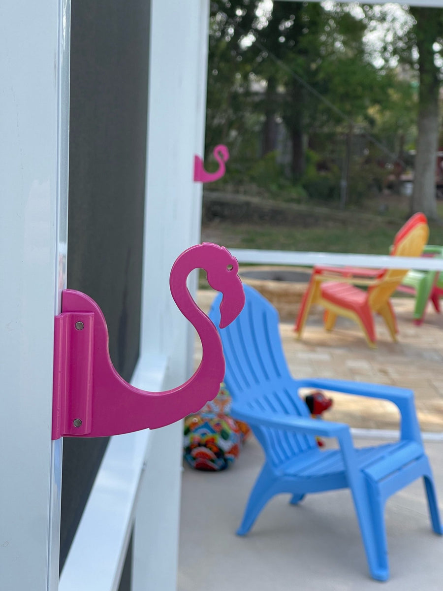 Pink flamingo hook on white post beside the yard.