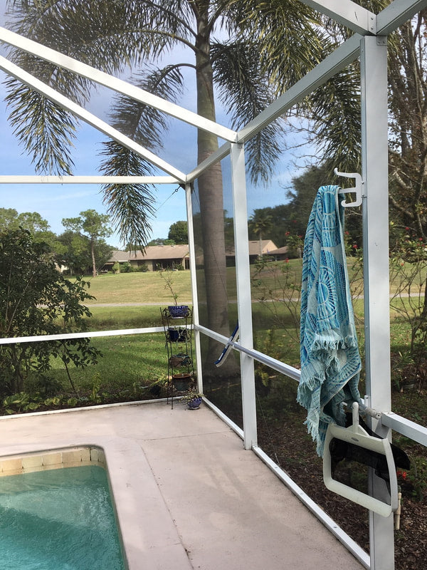 Towel on a hook on white enclosure post, pool corner.