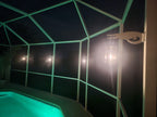 White alligator hanger on a lanai post holding a glowing lantern at night beside a lit pool.