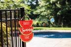 Anchor hook on a black aluminum fence post holding a watermelon Sweet Summer Time sign.