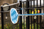 Silver anchor hook on a black aluminum fence post holding a pool skimmer net, string lights along fence.