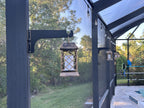 Black classic hanger on a dark lanai post holding a lantern beside a lawn.