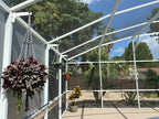 White classic hanger on a white pool-cage post holding a basket of purple trailing plants.