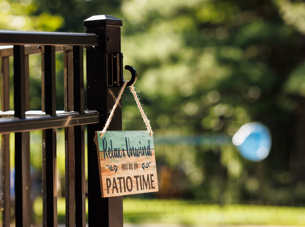 Black classic loop hook on a black aluminum fence post holding a Relax and Unwind sign.
