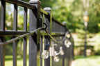 Black classic loop hooks on black aluminum fence posts holding a strand of string lights.