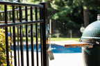 Black medium classic hook on a black aluminum fence post holding a grill spatula next to a green grill.