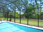 Wide view of a screened pool enclosure with dolphin hangers holding plants along the cage.