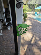 Lime green turtle mini table clamped to a dark lanai post on a brick paver patio.