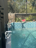 Two white turtle-shaped mini tables clamped to dark lanai posts beside a tiled pool wall.