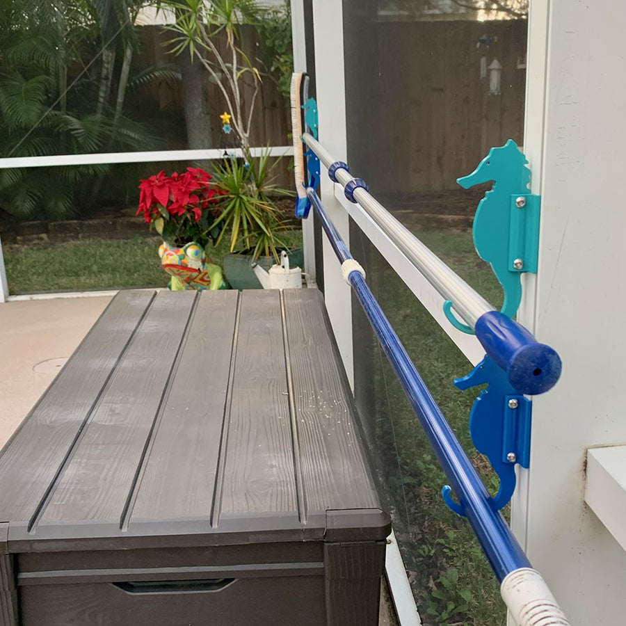 Teal seahorse hooks holding blue pool pole over storage box.