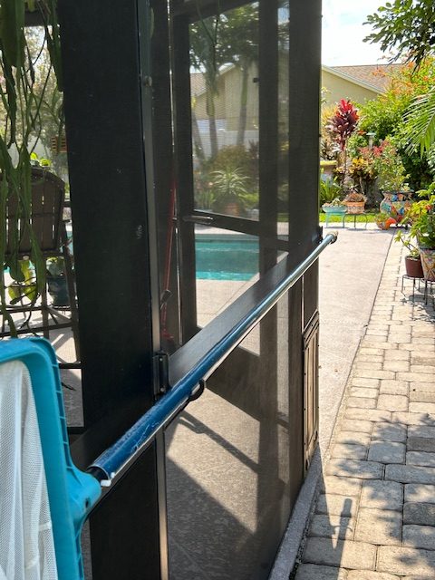 Sunny poolside patio with screen enclosure and garden.